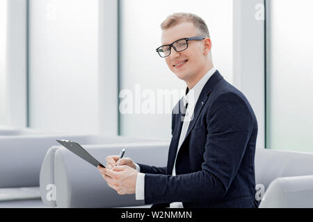 Imprenditore sottoscrive un documento aziendale seduta in ufficio lobby. foto con spazio di copia Foto Stock