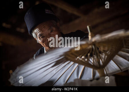 (190710) -- QIUBEI, luglio 10, 2019 (Xinhua) -- Zhang Ronghua controlla un olio-ombrello di carta in Xiangyang villaggio di Qiubei County, Zhuang e Miao prefettura autonoma di Wenshan, a sud-ovest della Cina di Provincia di Yunnan, Luglio 9, 2019. Zhang Ronghua, 89 e il nipote Zhang Guoqing sono gli unici eredi della tradizionale olio-ombrello di carta rendendo in Xiangyang Village. Xiangyang Village ha un oltre 400 anni di storia della realizzazione artigianale a carta oliata ombrelloni con gabbie di bambù. Fatta di carta oliata e cornice di bambù, olio-ombrello di carta è un cinese tradizionale artigianato. L'artigianalità inclu Foto Stock