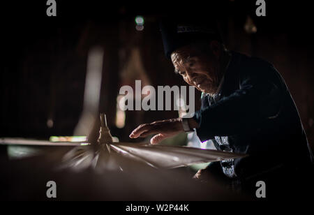 (190710) -- QIUBEI, luglio 10, 2019 (Xinhua) -- Zhang Ronghua controlla un olio-ombrello di carta in Xiangyang villaggio di Qiubei County, Zhuang e Miao prefettura autonoma di Wenshan, a sud-ovest della Cina di Provincia di Yunnan, Luglio 9, 2019. Zhang Ronghua, 89 e il nipote Zhang Guoqing sono gli unici eredi della tradizionale olio-ombrello di carta rendendo in Xiangyang Village. Xiangyang Village ha un oltre 400 anni di storia della realizzazione artigianale a carta oliata ombrelloni con gabbie di bambù. Fatta di carta oliata e cornice di bambù, olio-ombrello di carta è un cinese tradizionale artigianato. L'artigianalità inclu Foto Stock