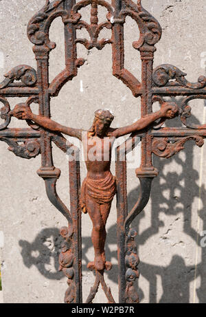 Sint Gillis waas, Belgio, 08 luglio 2019. Vecchio arrugginito croce con Gesù Cristo, l'ombra cade su un sfondo di calcestruzzo Foto Stock