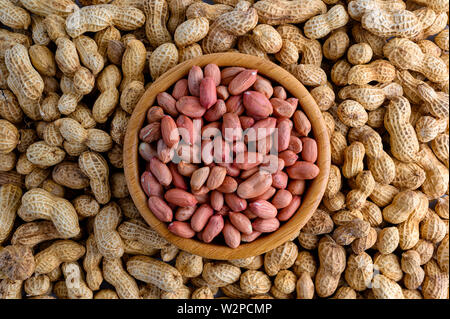 Ciotola di legno dei pomodori pelati noccioline e Arachidi in guscio di noce Foto Stock