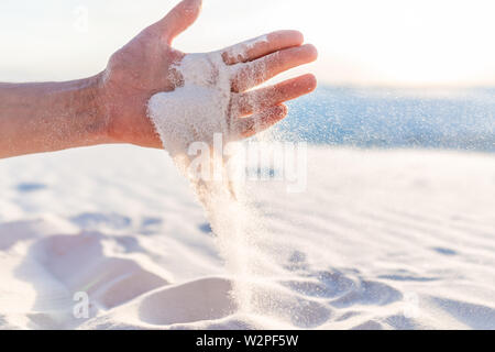 White Sands Dunes National Monument man mano che tiene la sabbia caduta di grani in Nuovo Messico al tramonto Foto Stock