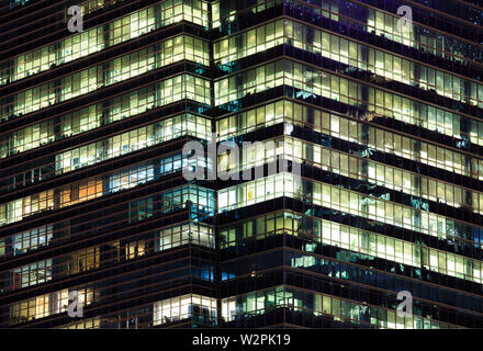 A tarda notte le ore di lavoro straordinario in un ufficio moderno facciata di edificio Foto Stock