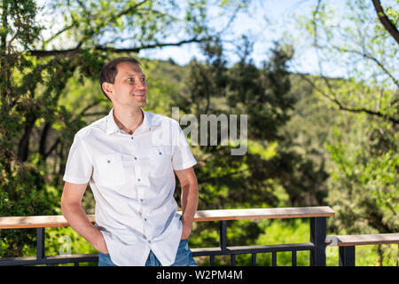 Giovane uomo felice dalla ringhiera recinto nel lusso moderno outdoor spring garden nel portico del cortile sul retro di casa in casa zen Foto Stock