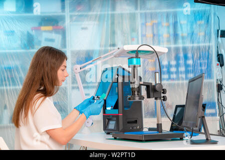 Lavoratore di sesso femminile nel controllo di resina LCD / DLP / SLA stampante 3D nel laboratorio di tecnologia Foto Stock
