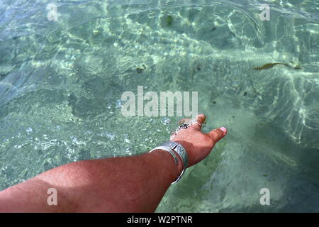 Donna di mano con argento braccialetti e anelli, spruzzi di acqua oceanica Foto Stock