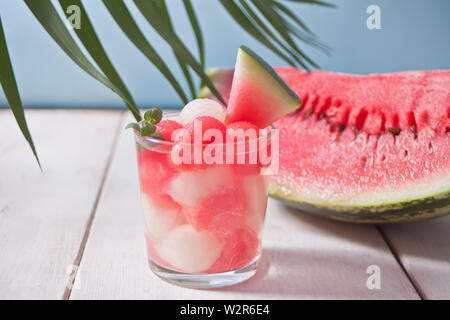 Macedonia di frutta con melone ed anguria sfere in vetro e pice di anguria sotto la foglia di palma sullo sfondo bianco Foto Stock