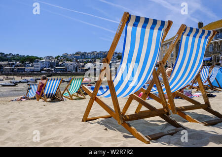 Due sdraio vuote fianco a fianco sul porto Beach di St Ives in Cornovaglia Foto Stock