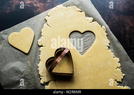 Angolo alto close up a forma di cuore i cookie tagliato fuori della pasta biscotto. Foto Stock