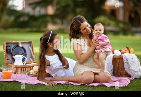 Donna con un picnic con le sue figlie. Foto Stock