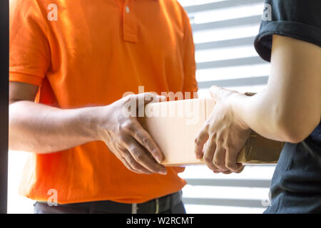 Donna mano accetta una consegna di scatole da deliveryman. Consegna a domicilio Servizio di corriere e concetto di spedizione Foto Stock