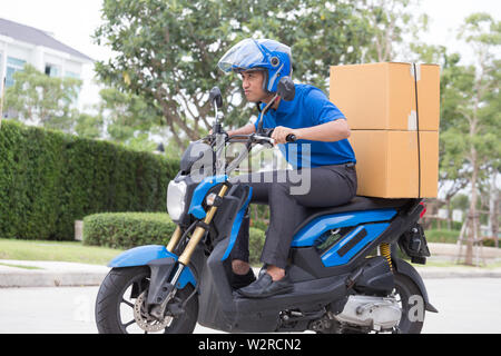 Ragazzo delle consegne sul motociclo con tronco casella di pacchi di guida veloce in fretta. Corriere consegna ordine online. Express consegna entro un intervallo di tempo specificato da s Foto Stock