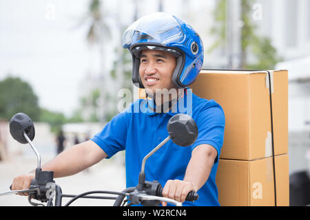 Ragazzo delle consegne sul motociclo con tronco casella di pacchi di guida veloce in fretta. Corriere consegna ordine online. Express consegna entro un intervallo di tempo specificato da s Foto Stock