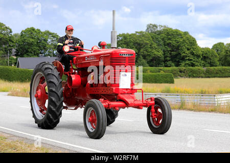 Kimito, Finlandia. Luglio 6, 2019. Unità uomo red International Harvester Farmall M trattore, anno 1951, su Kimito Tractorkavalkad, vintage parata del trattore. Foto Stock