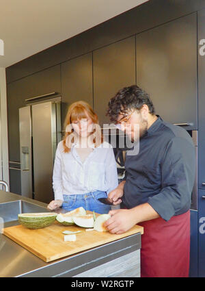 I cuochi il taglio di un melone freschi - fresco raccolte melone verde - Chef che mostra un apprendista come tagliare il melone - fresco melone verde Foto Stock