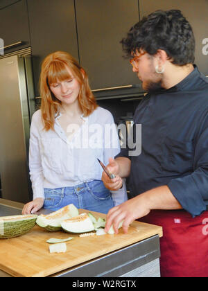 Ragazza capelli rossi allievo cook - Due cuochi di taglio - melone fresco melone verde Foto Stock