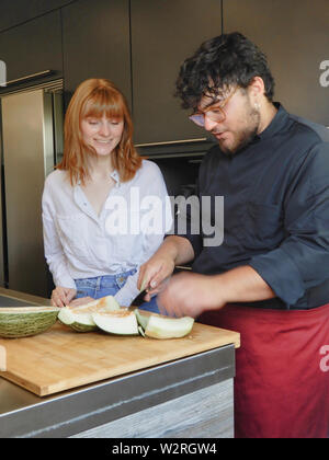 Cuocere il taglio di melone accompagnato da una donna con i capelli rossi - Redheaded ragazza sorridente Foto Stock