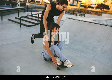 Giovane uomo e donna per divertirsi con lo skateboard in skate park. Giovane lo skateboard a skate park. Foto Stock