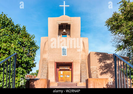 Santa Fe, Stati Uniti d'America - 14 Giugno 2019: San Miguel cappella missione chiesa più antica negli Stati Uniti con adobe pueblan architettura di stile, croce blu e blu Foto Stock