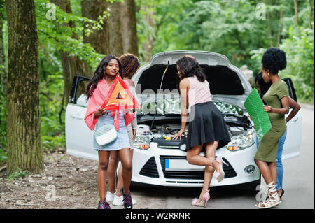 Il gruppo di cinque African American Traveler ragazze guardando broken auto aprire il cofano. Foto Stock