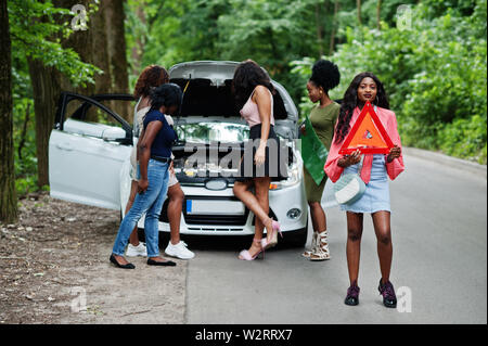 Il gruppo di cinque African American Traveler ragazze guardando broken auto aprire il cofano. Foto Stock