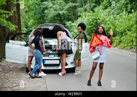 Il gruppo di cinque African American Traveler ragazze guardando broken auto aprire il cofano. Foto Stock