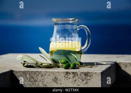 Bottiglia con olio di oliva e olio di oliva fresco frutta sul cielo blu sullo sfondo Foto Stock