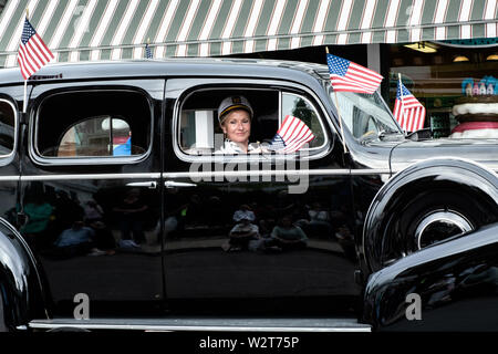 Una donna comanda un antico passato di automobile di spettatori durante il Windjammer giorni parata nel piccolo borgo midcoast di Boothbay Harbor, Maine. Foto Stock