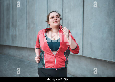 Voglio perdere peso giovane attraente più taglia donna in abiti sportivi che corrono all'aperto al mattino. Stile di vita sano. Perdita di peso. Concetto di sport Foto Stock