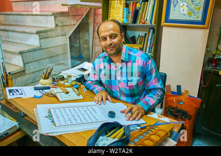 KASHAN, IRAN - 23 ottobre 2017: il ritratto del calligrafo, riscrivere le sure del Corano, seduto nella sua bottega, il 23 ottobre a Kashan. Foto Stock