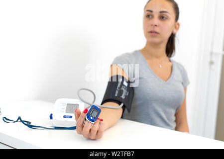 Giovane bella ragazza misure del polso e della pressione sanguigna presso la reception di un terapeuta. Foto Stock