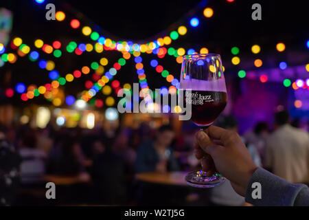 Belgioioso, Italia / 07. 08.2019: Roze Jazz Rizling giorni a Veszprém summer festival evento con luce bokeh di fondo e un bicchiere di vino rosso Foto Stock