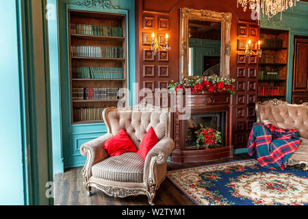 Luxury classic interno della libreria di casa. Salotto con libreria, libri, poltrona, divano letto e camino. Pulire e decorazione moderna con eleganti f Foto Stock