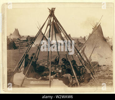 Home della signora cavallo americano. Visita squaws presso la sig.ra a casa nel campo ostile; Oglala donne e bambini seduti all'interno di una scoperta tende Tepee telaio in un accampamento--la maggior parte sono alla ricerca di distanza dalla telecamera--probabilmente su o in prossimità di Pine Ridge Prenotazione. Foto Stock