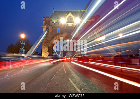 Veicoli che passano oltre il Tower Bridge sul fiume Tamigi a Londra, Regno Unito. Foto Stock
