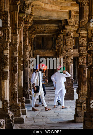 NEW DELHI, India - CIRCA NOVEMBRE 2018: gli abitanti del posto a piedi attorno a intricate sculture in pietra sul chiostro colonne a Quwwat ul-Islam moschea di Qutb M Foto Stock