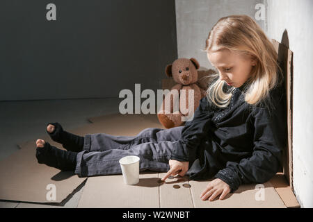 Senzatetto bambina contare monete Foto Stock