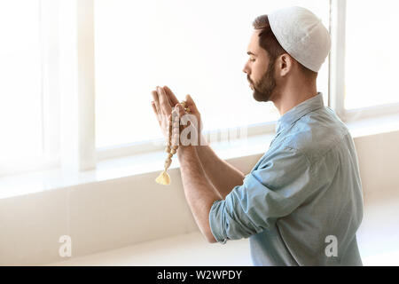 Giovani Musulmani uomo che prega in ambienti interni Foto Stock