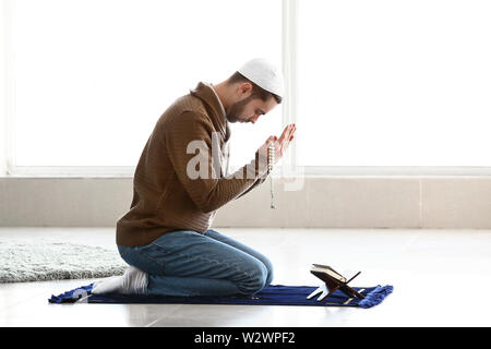 Giovani Musulmani uomo che prega in ambienti interni Foto Stock