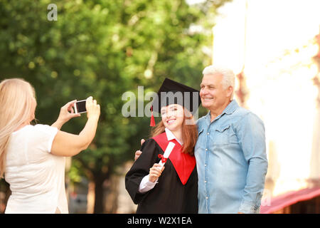 Donna prendendo foto di suo marito e figlia sul giorno di graduazione Foto Stock