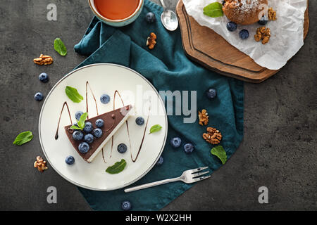 Gustosi dessert con mirtillo e tè su sfondo grigio Foto Stock