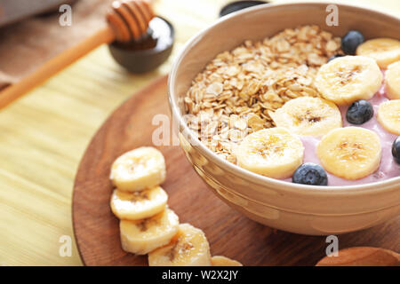 Yogurt gustosi con mirtillo, fiocchi di avena e banana nella ciotola sul tavolo Foto Stock