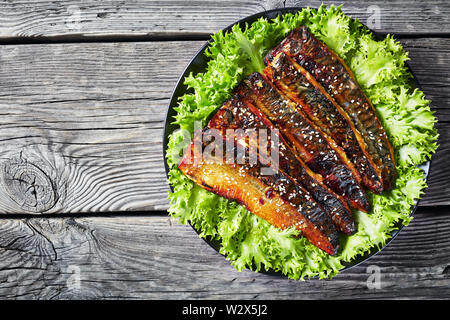 Arrosto di filetti di sgombro pesce servite con lattuga su una piastra bianca su una tavola in legno rustico, vista da sopra, flatlay, spazio vuoto Foto Stock