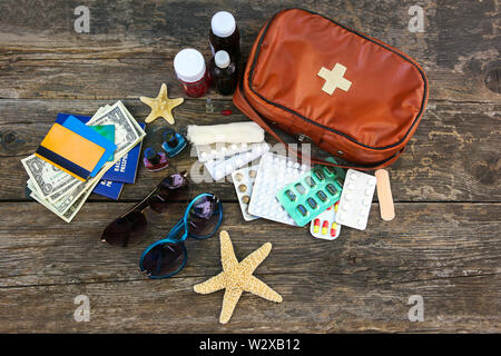 Estate donna accessori sulla spiaggia per la vostra vacanza al mare e kit di primo soccorso sul vecchio sfondo di legno. Concetto di medicinali necessari in viaggio. Vista dall'alto. Foto Stock