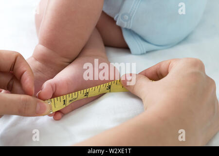 Misurare le dimensioni del piede baby, corpo infantile concetto di sviluppo, tre del mese precedente Foto Stock