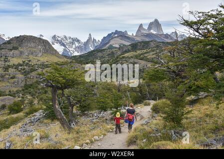 Giovane donna e giovane ragazzo in escursioni a piedi nella parte anteriore della gamma della montagna con il Monte Fitz Roy vicino a El Chalten, parco nazionale Los Glaciares, Provincia di Santa Cruz Foto Stock