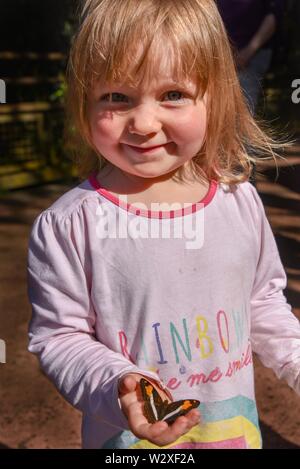 Bambina con una farfalla sulla sua mano, Puerto Iguazú, in Argentina Foto Stock