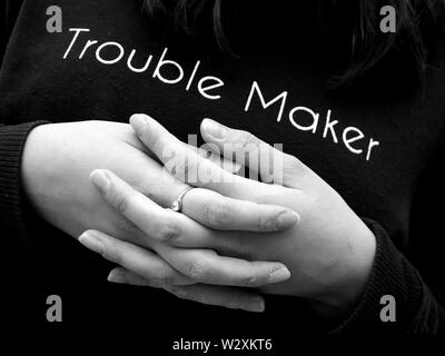 Ragazza adolescente con mani incrociate indossando "trouble maker" ponticello. (Giustapposizione di sentimenti durante l adolescenza). Foto Stock