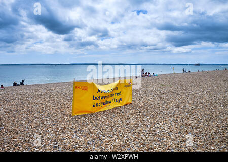 Nuvole scure sulla spiaggia a Southsea con il segno RNLI per bagnini Foto Stock