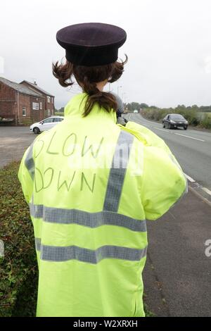 Sefton, Merseyside, Regno Unito. 11 luglio 2019. Poliziotta armata con fotocamera velocità provoca il passaggio agli automobilisti in Southport Rd, Sefton a lento in giù non appena essi scorgere la sua. In realtà il funzionario di polizia è uno spaventapasseri in un alto-vis jacket la velocità fotocamera è realizzato da un vuoto bottiglia di sbianca coperta con un foglio di alluminio. Denominato 'Speedo' è stato creato da 71-anno-vecchio consigliere parrocchiale Edie Papa chi corre in vista della Chiesa Farm Shop in Southport Road, Lydiate, dopo una stringa del traffico su strada gli incidenti causati da persone che guidano per disattenzione o troppo veloce. Credit:Ken Biggs/Alamy Live News Foto Stock